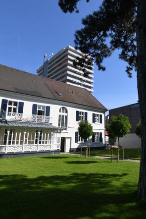 Blick vom Garten auf Jugendstil-Villa, weißer Anstrich, dahinter Burghof, Hochhaus am Marktplatz