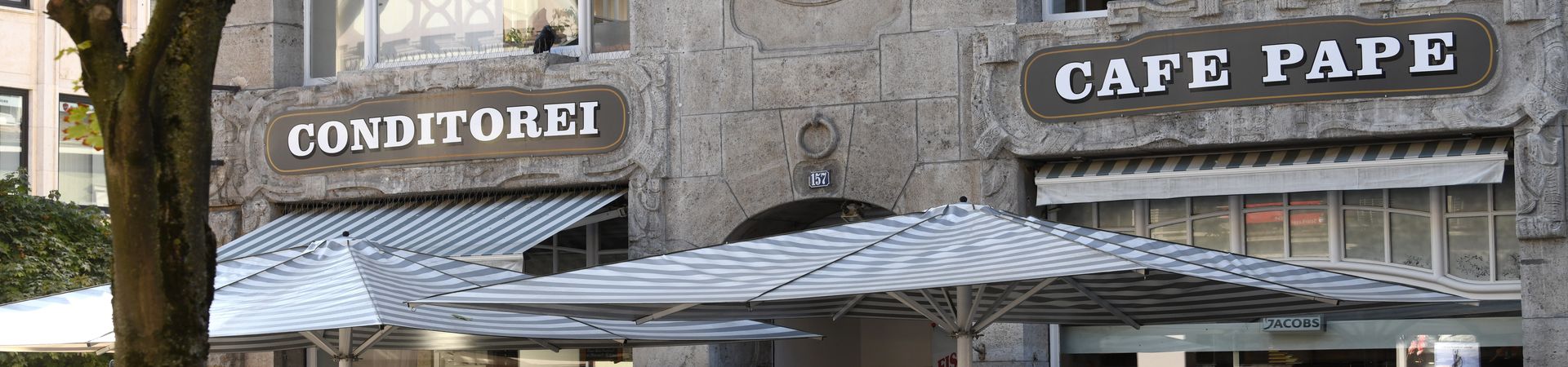 Blick auf blau-weiße Schirme und Inschrift Conditorei Café Pape